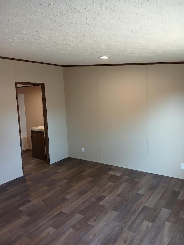 unfurnished room with dark wood-type flooring, ornamental molding, and a textured ceiling