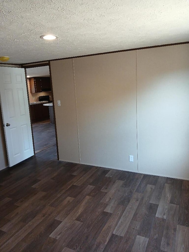 spare room with dark hardwood / wood-style floors and a textured ceiling