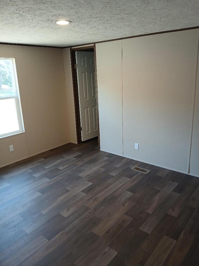 empty room with dark wood-type flooring and a textured ceiling