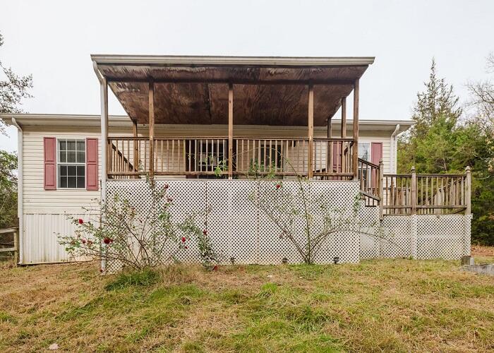 back of property with a deck and a lawn