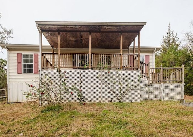 back of property with a deck and a lawn