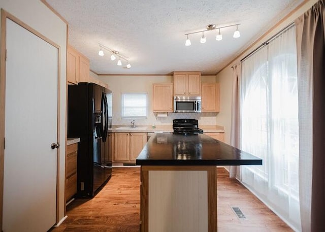 kitchen with crown molding, a center island, light hardwood / wood-style flooring, a textured ceiling, and black appliances