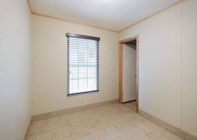 unfurnished room featuring ornamental molding and a textured ceiling