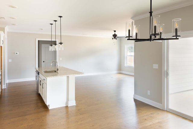 kitchen with sink, white cabinetry, light stone counters, an island with sink, and pendant lighting