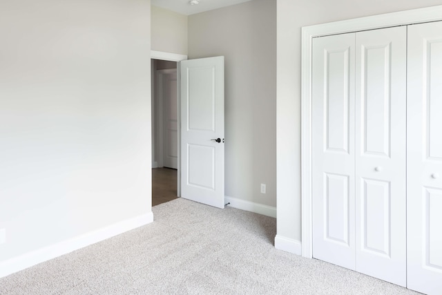 unfurnished bedroom featuring light colored carpet and a closet