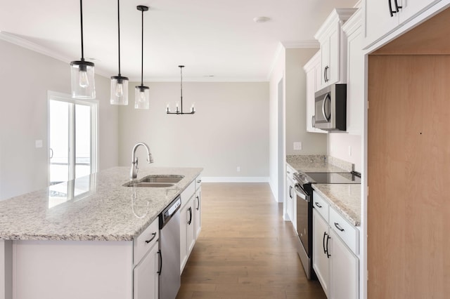 kitchen with appliances with stainless steel finishes, sink, white cabinets, hanging light fixtures, and a center island with sink