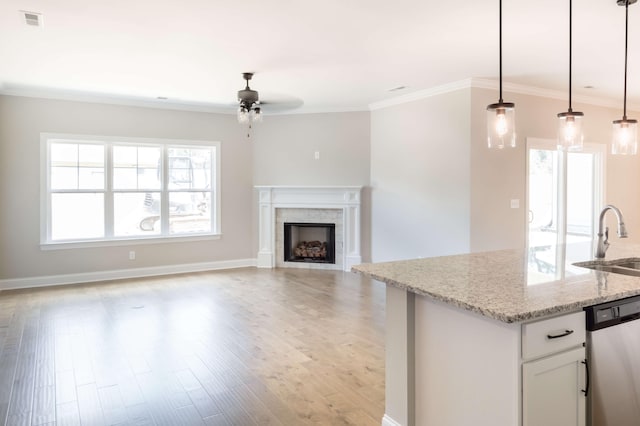 kitchen with pendant lighting, dishwasher, sink, white cabinets, and light stone counters