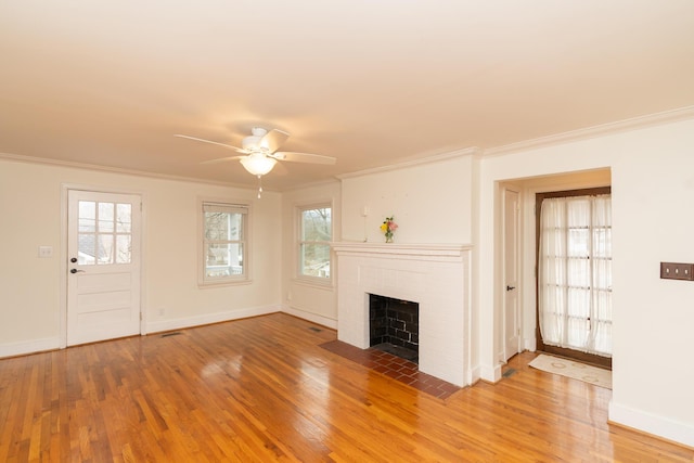 unfurnished living room with a brick fireplace, ornamental molding, hardwood / wood-style floors, and ceiling fan