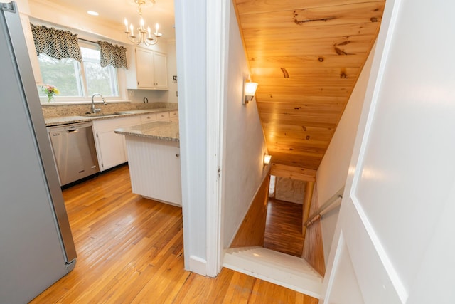 kitchen featuring white cabinetry, stainless steel appliances, sink, and hanging light fixtures