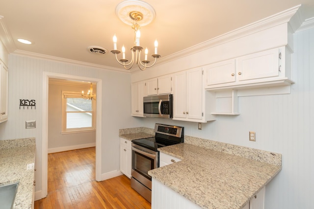 kitchen with appliances with stainless steel finishes, white cabinets, a chandelier, hanging light fixtures, and light stone countertops