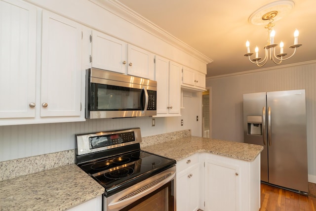 kitchen with pendant lighting, ornamental molding, stainless steel appliances, and white cabinets