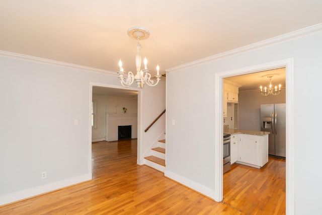 spare room with an inviting chandelier, crown molding, and light hardwood / wood-style flooring