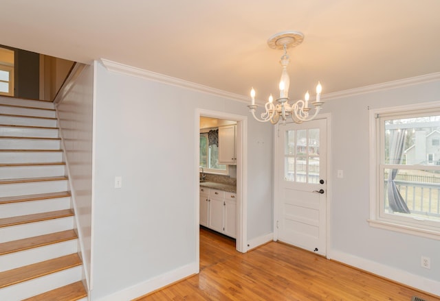 unfurnished dining area featuring crown molding, a chandelier, and light wood-type flooring