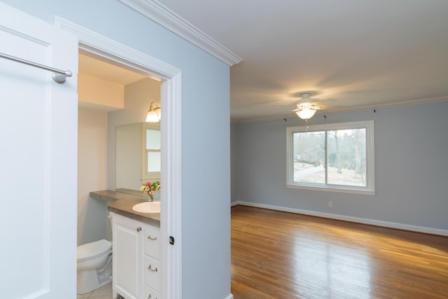 bathroom featuring hardwood / wood-style flooring, ornamental molding, vanity, ceiling fan, and toilet