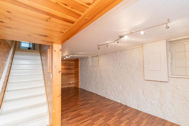 basement featuring wood ceiling, wood-type flooring, wood walls, and track lighting