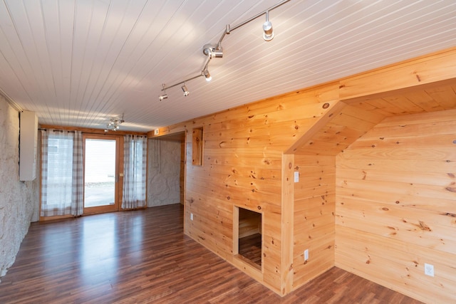 interior space featuring rail lighting, dark hardwood / wood-style floors, wood ceiling, and wood walls