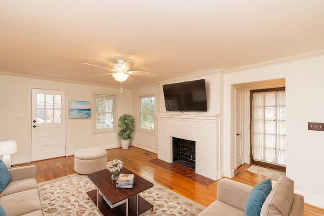 living room featuring a brick fireplace, crown molding, and wood-type flooring