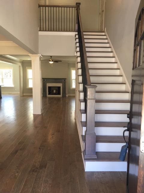 stairs featuring ceiling fan, hardwood / wood-style floors, and ornate columns