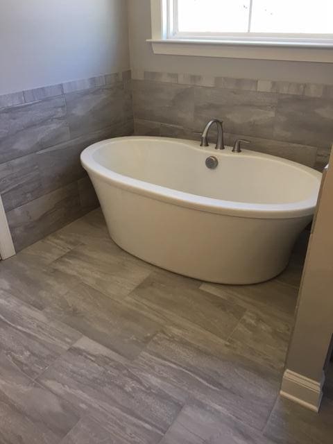 bathroom featuring a washtub and tile walls