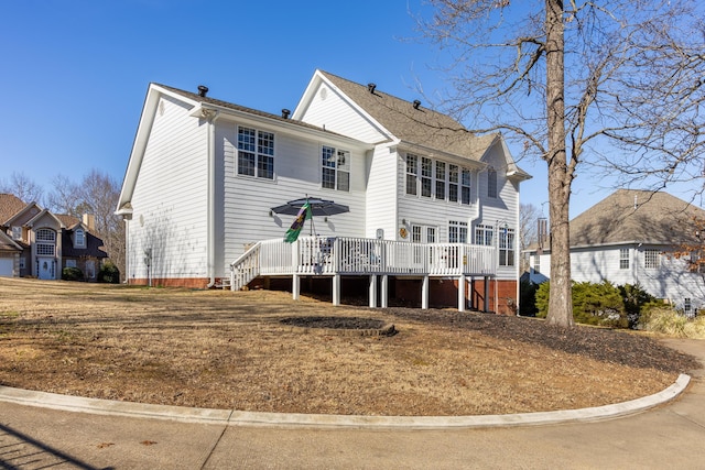 back of property featuring a wooden deck and a lawn