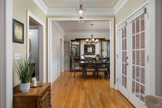 dining space with ornamental molding, a chandelier, light hardwood / wood-style floors, and french doors