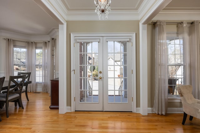 doorway to outside with crown molding, a chandelier, light wood-type flooring, and french doors