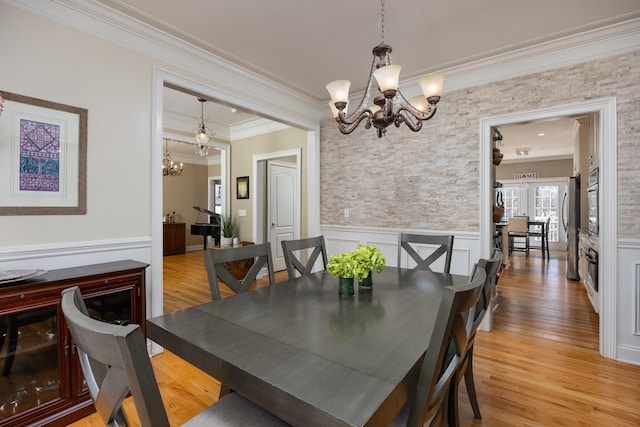 dining room featuring crown molding, light hardwood / wood-style floors, and a notable chandelier