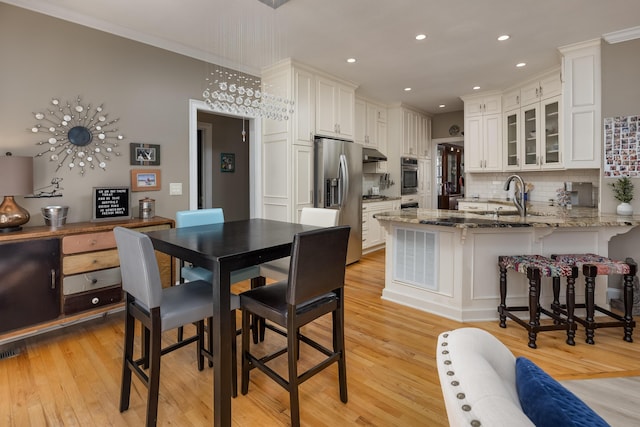 kitchen with a breakfast bar area, white cabinetry, stone countertops, stainless steel fridge with ice dispenser, and kitchen peninsula