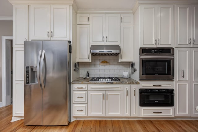 kitchen featuring light stone counters, white cabinetry, appliances with stainless steel finishes, and exhaust hood