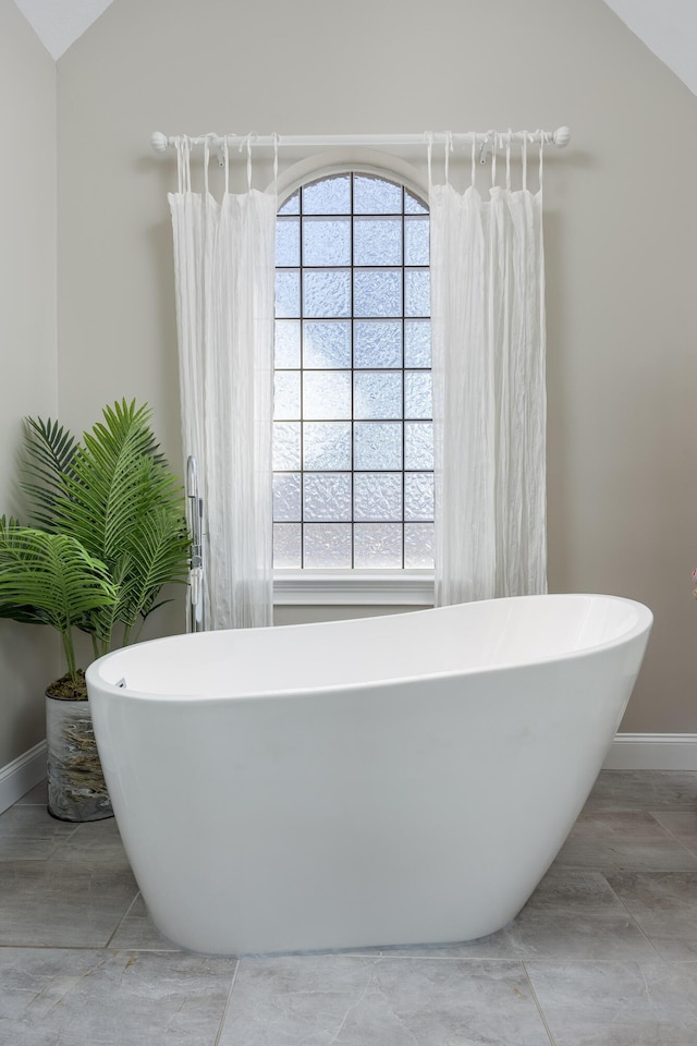 bathroom featuring lofted ceiling and a washtub