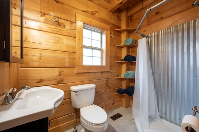 bathroom with a shower with curtain, wooden walls, sink, and toilet