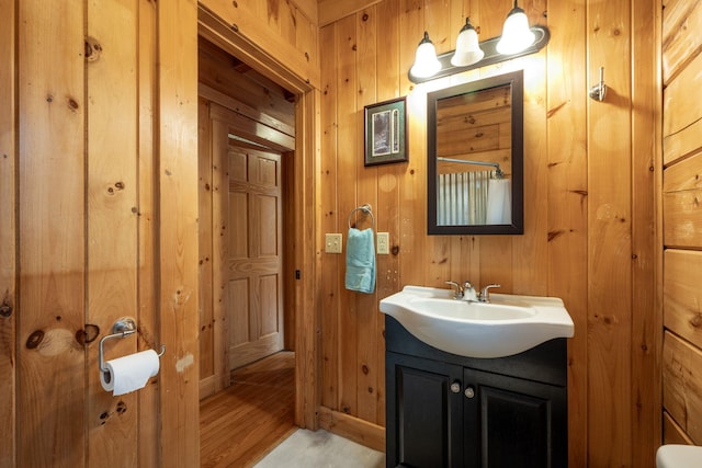 bathroom featuring vanity, hardwood / wood-style floors, and wooden walls