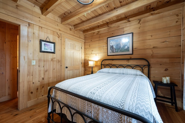 bedroom with beamed ceiling, hardwood / wood-style floors, and wooden walls