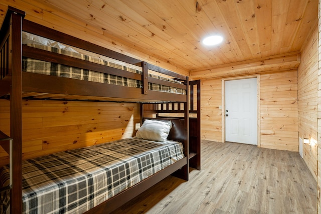 bedroom featuring wooden walls, light hardwood / wood-style floors, and wooden ceiling