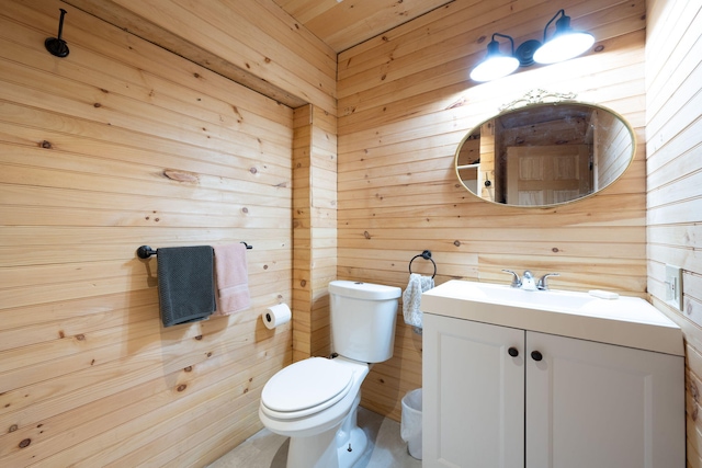 bathroom with vanity, wooden walls, and toilet