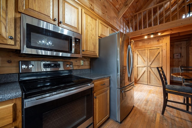 kitchen featuring wooden ceiling, light wood-type flooring, appliances with stainless steel finishes, wooden walls, and beamed ceiling