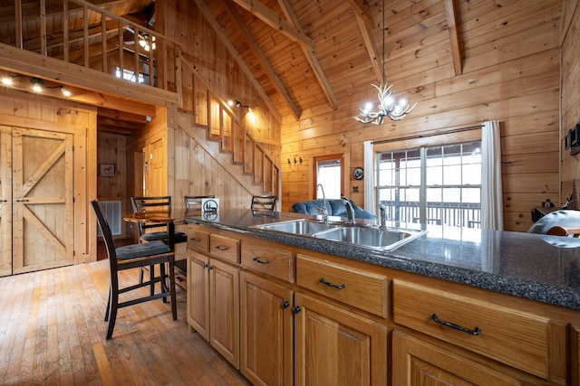 kitchen featuring pendant lighting, wooden walls, sink, and beam ceiling