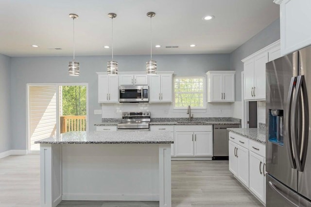 kitchen with hanging light fixtures, appliances with stainless steel finishes, sink, and white cabinets