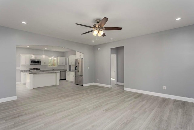 kitchen featuring a kitchen island, pendant lighting, white cabinets, stainless steel appliances, and light wood-type flooring