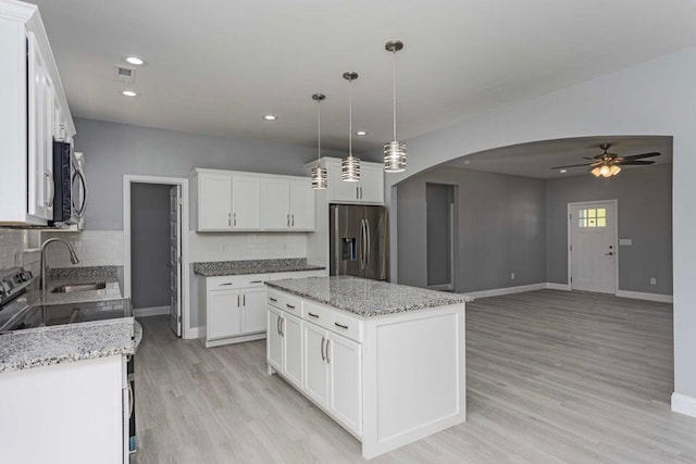 kitchen with a kitchen island, appliances with stainless steel finishes, white cabinets, and decorative backsplash