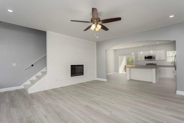 unfurnished living room with sink, a fireplace, light hardwood / wood-style floors, and ceiling fan