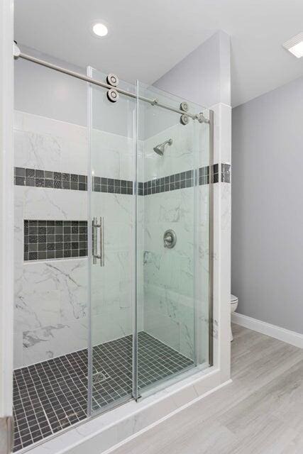 bathroom featuring an enclosed shower, hardwood / wood-style floors, and toilet