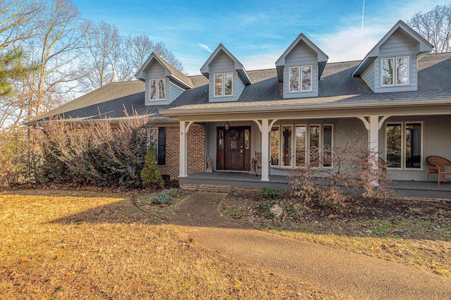 cape cod house featuring a porch and a front lawn