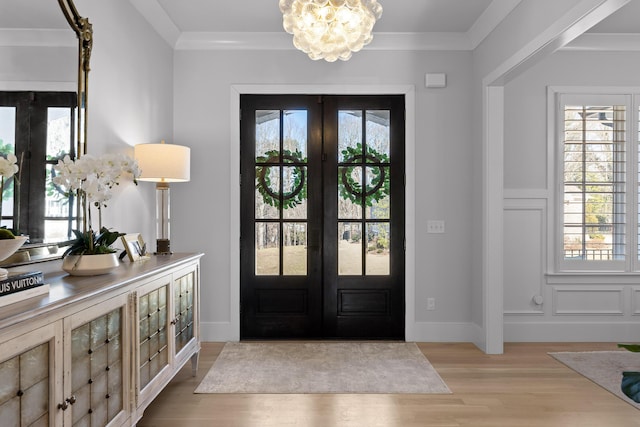 entrance foyer featuring french doors, ornamental molding, and light hardwood / wood-style flooring