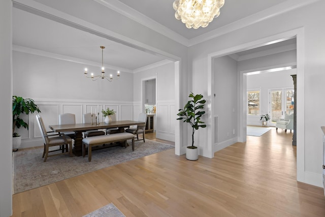 dining space with an inviting chandelier, light hardwood / wood-style flooring, and ornamental molding