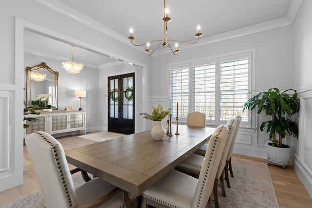 dining space featuring a notable chandelier, crown molding, light hardwood / wood-style flooring, and french doors