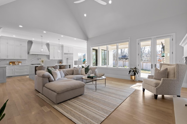 living room featuring high vaulted ceiling, light hardwood / wood-style floors, and french doors