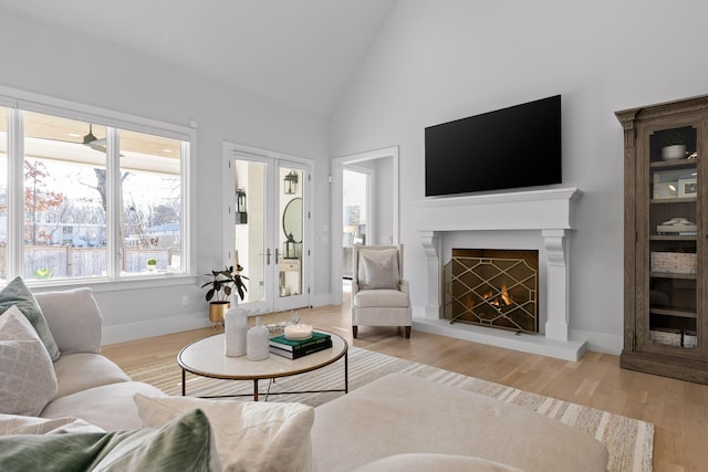 living room with hardwood / wood-style flooring, high vaulted ceiling, and french doors