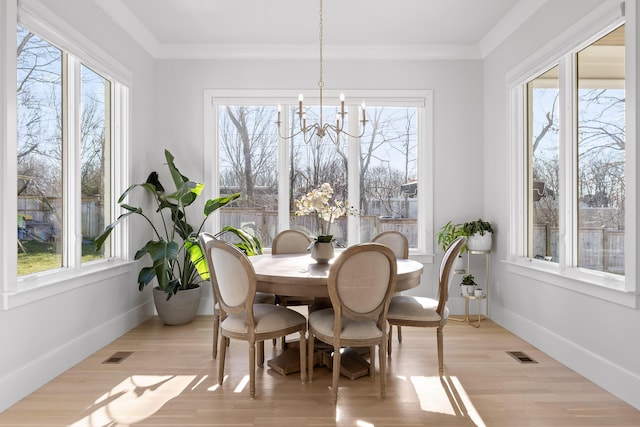 dining area featuring crown molding, a notable chandelier, and light wood-type flooring