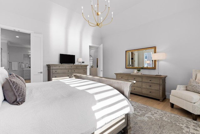 bedroom with ensuite bath, an inviting chandelier, and light hardwood / wood-style flooring